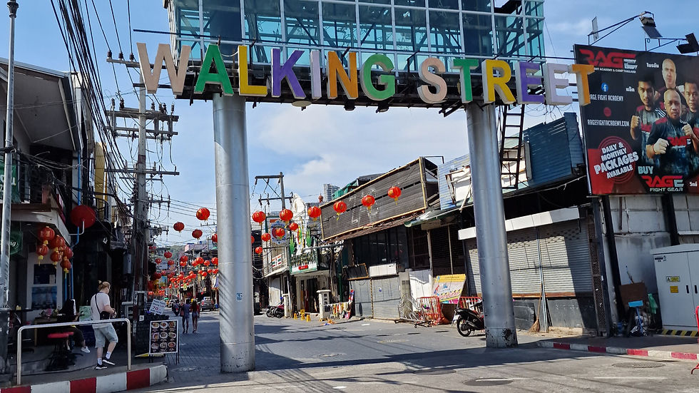 A street scene features an entrance sign reading "WALKING STREET" in colorful letters. Red lanterns hang overhead, and several buildings and a few people are visible. A billboard is on the right side of the image.