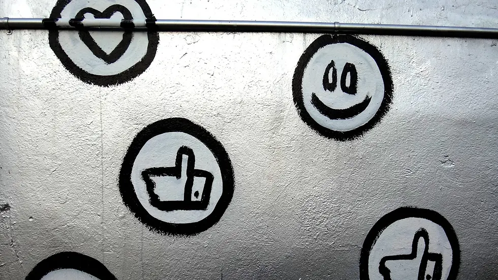 Black stenciled icons on a gray wall include hearts, thumbs up, and a smiley face, creating a playful and urban atmosphere.