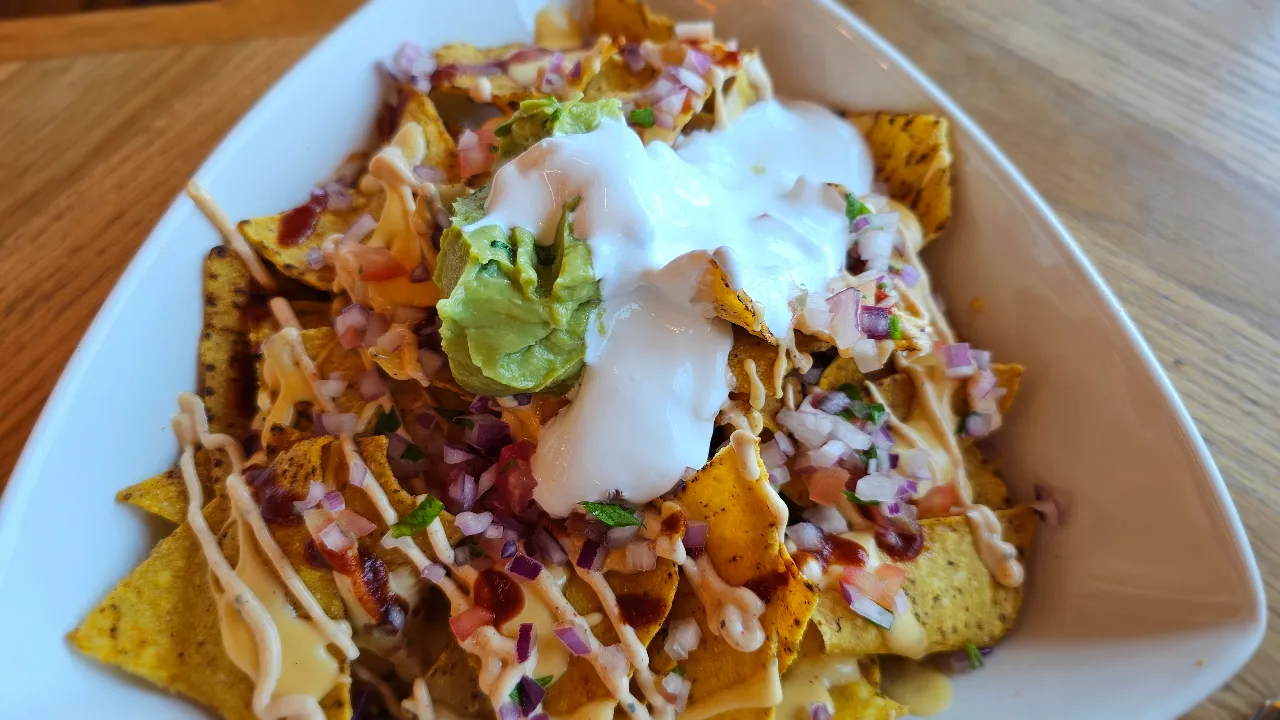 Delicious loaded nachos with melted cheese, sour cream, and toppings served at Giraffe World Kitchen restaurant in Hamad International Airport, Doha, Qatar.