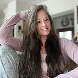 Smiling portrait of Jenn, co-founder of Closer Lives, with long brown hair, set in a clean, modern circular frame.