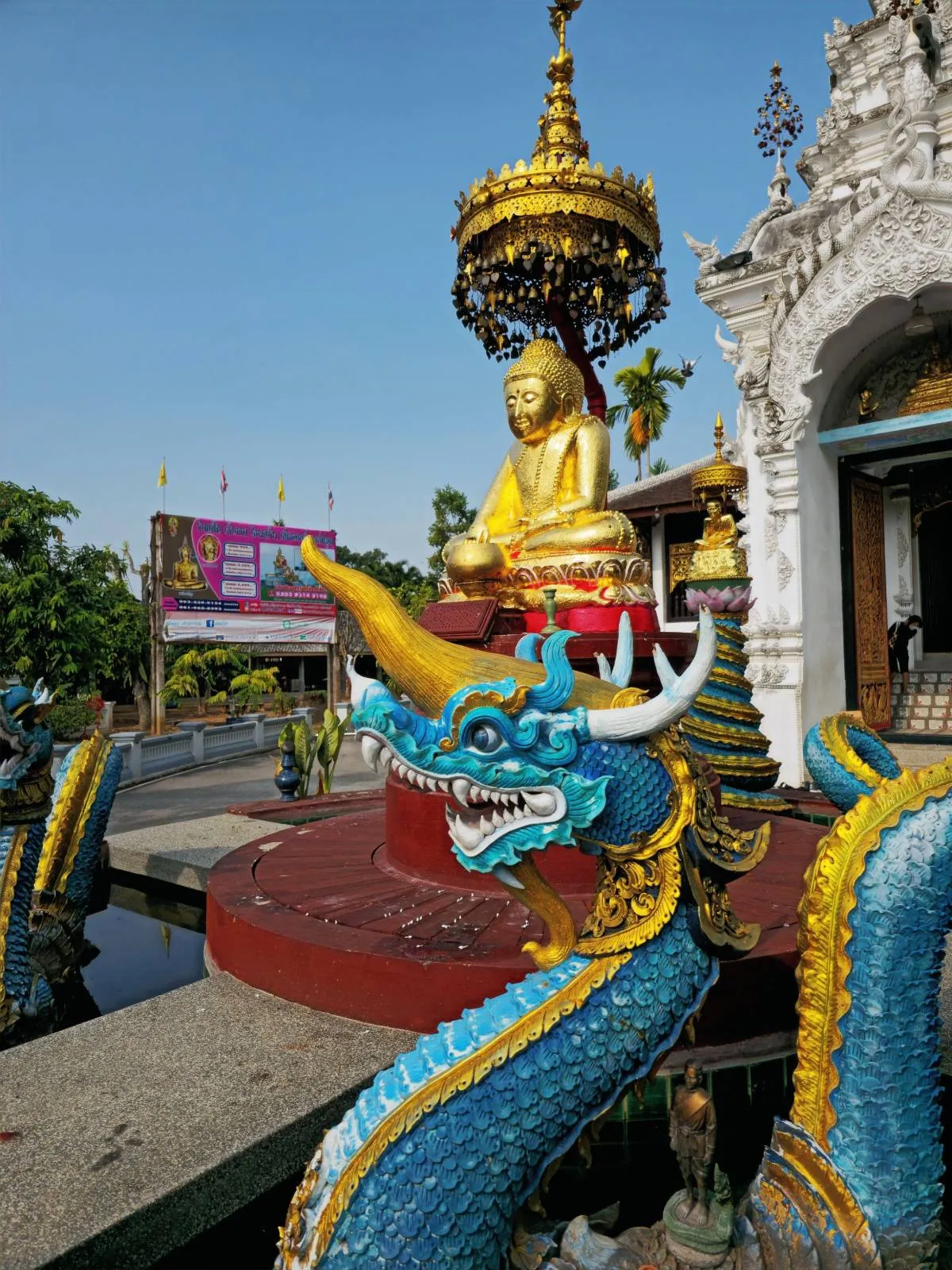 Golden Buddha shrine with blue naga sculptures at Wat Sri Mung Muang, Doi Saket.