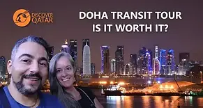 Jenn and Leon from Closer Lives on a Discover Qatar Doha Transit Tour layover with the city skyline behind them.