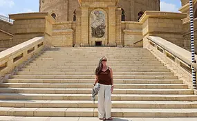 Jenn standing on wide stone steps outside the Church of St George in Giza, Egypt, with ornate stonework and an arched entrance behind her.