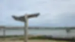 Wooden signpost indicating directions to the footpath and England coast path near a scenic waterfront with boats and a cloudy sky.