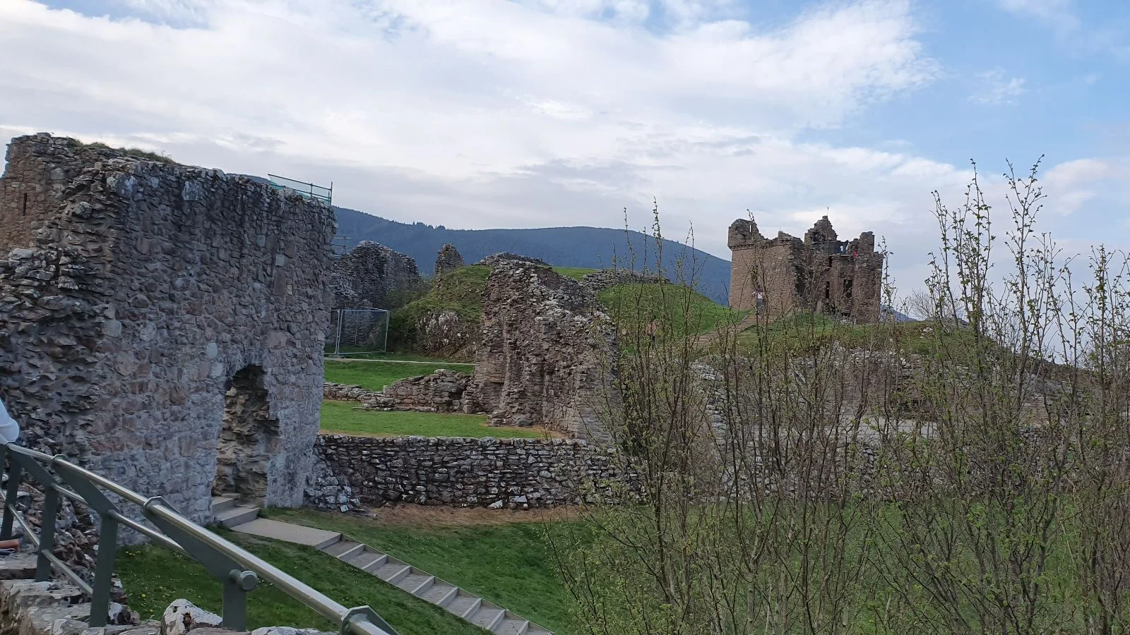 Urquhart Castle ruins with scattered stone walls and structures set against the Loch Ness landscape.