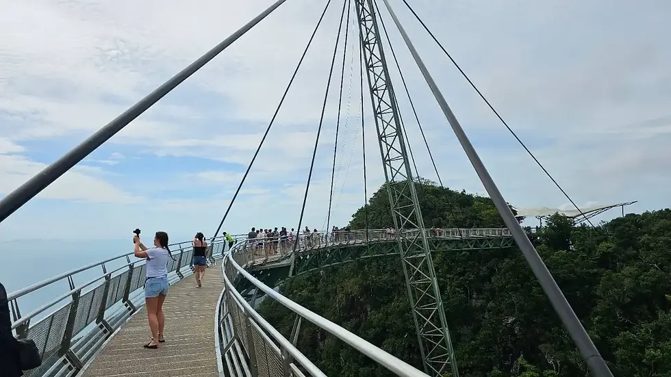 People walking across the curved Langkawi SkyBridge, a famous pedestrian bridge suspended high above the jungle canopy in Langkawi, Malaysia.