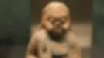 Clay figure of a person with closed eyes, textured hair, and blue markings, set against a blurred background. The mood is serene.