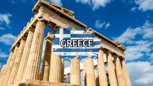 Ancient columns of the Parthenon in Athens, Greece, against a blue sky with clouds. The word "GREECE" and a Greek flag graphic overlay on the image.