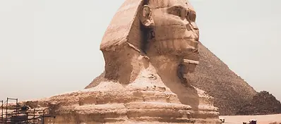 The Great Sphinx of Giza with a pyramid rising behind it in the Egyptian desert.