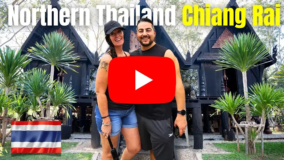 Smiling couple in front of black Thai house in Chiang Rai, surrounded by palm trees. Text: Northern Thailand, Chiang Rai. Thai flag visible.