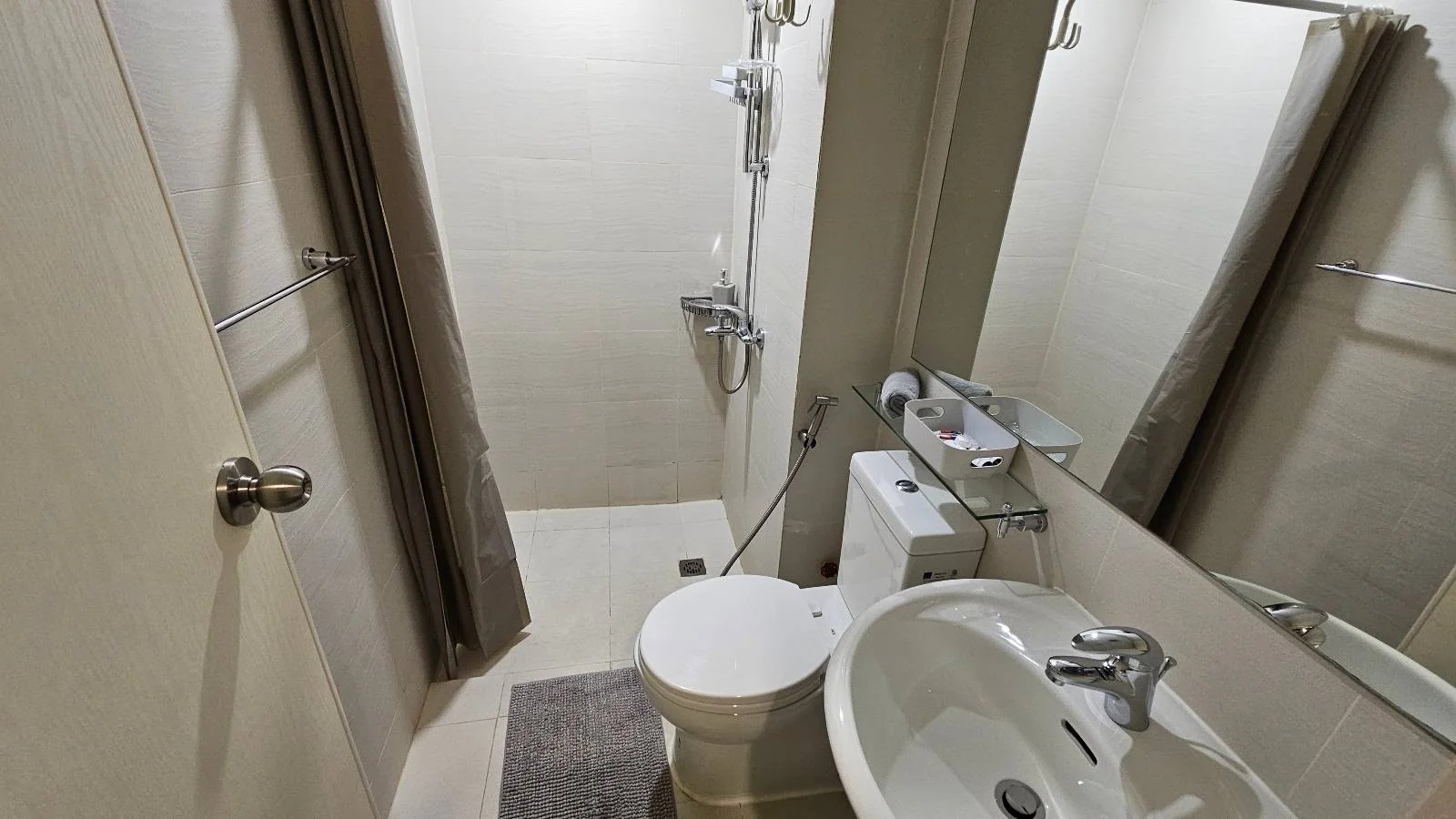 A small bathroom with a shower, toilet and wash basin.