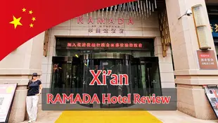 Person stands outside Ramada Hotel, Xi'an. Text displays "RAMADA Hotel Review." Red flag and Chinese signage above entrance.