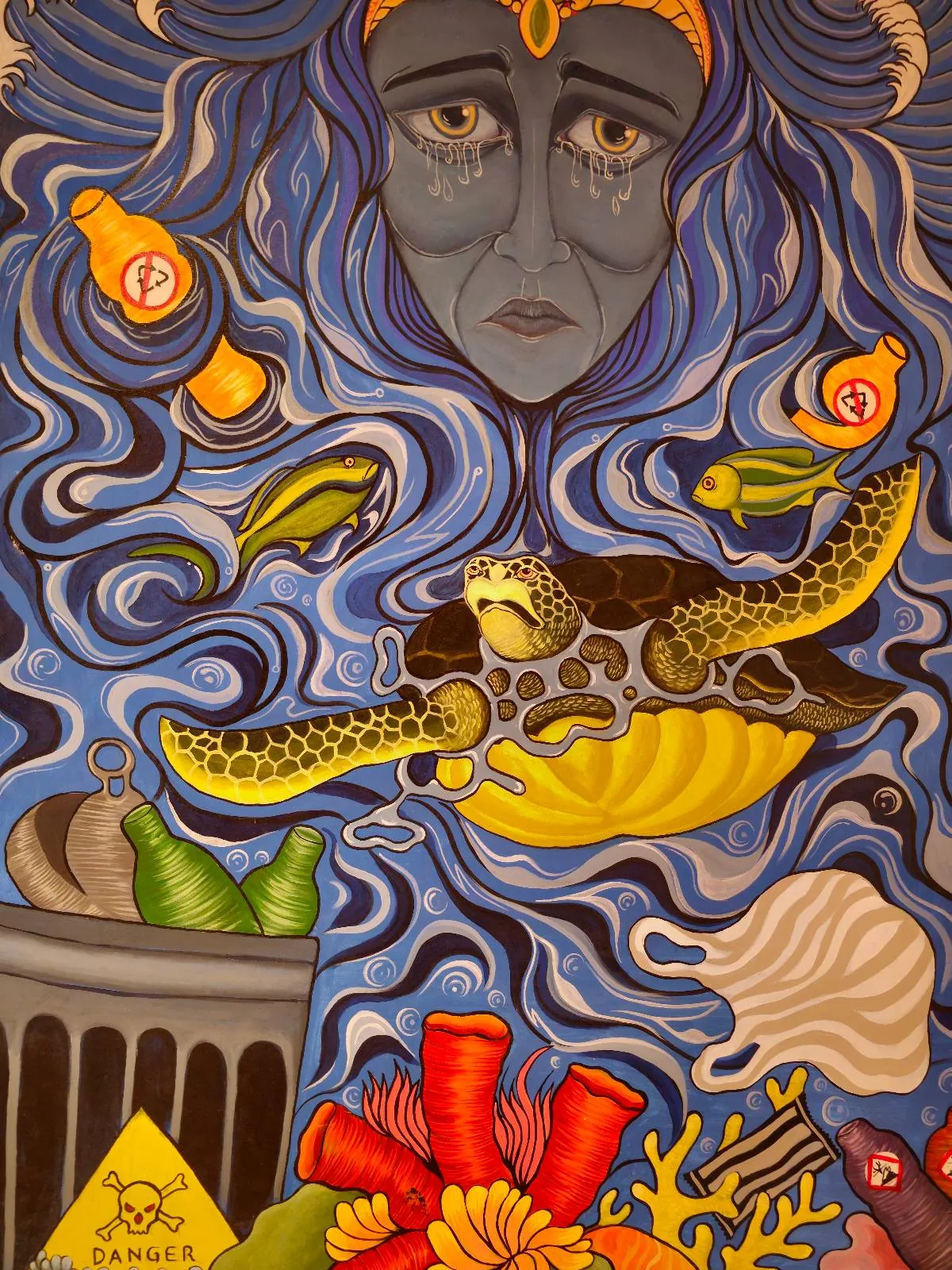 A surreal artwork shows a sad blue face surrounded by swirling water, sea life, and marine trash like bottles, a can, and gloves. A turtle swims in the center, highlighting ocean pollution.
