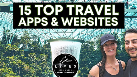 Two smiling people pose in front of a lush indoor garden with a waterfall. Large text above reads "15 Top Travel Apps & Websites." A circular logo at the bottom includes "Lives" and travel lifestyle branding.