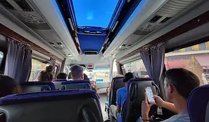 Interior of a small passenger bus during a land border crossing in North Macedonia, with seated travellers and overhead skylight visible.