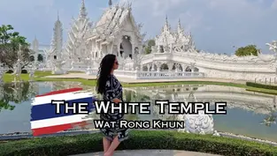 Woman in black dress standing before the ornate White Temple, Wat Rong Khun, with blue sky. Text: "The White Temple."