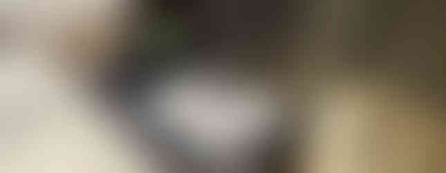 A bathroom counter with two green pump bottles, neatly arranged toiletries in white packaging, and a small soap dish next to a sink and a tiled shower area.