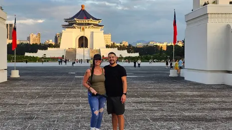 Jenn and Leon standing in front of Chiang Kai-shek Memorial Hall in Taipei, Taiwan, with the monument visible behind them.