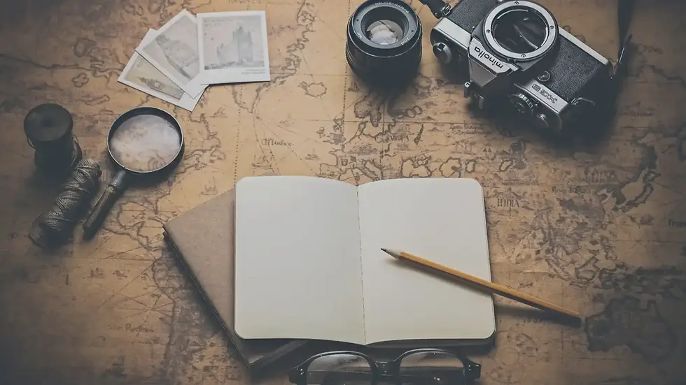 A blank notebook with a pencil rests on an old-fashioned world map, surrounded by a magnifying glass, twine, camera, and envelope.