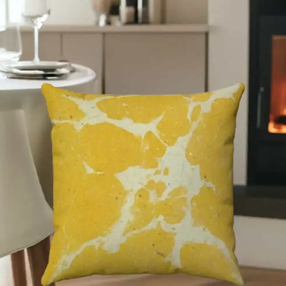 A decorative yellow cushion with white abstract patterns is placed on a wooden chair in a cozy room.