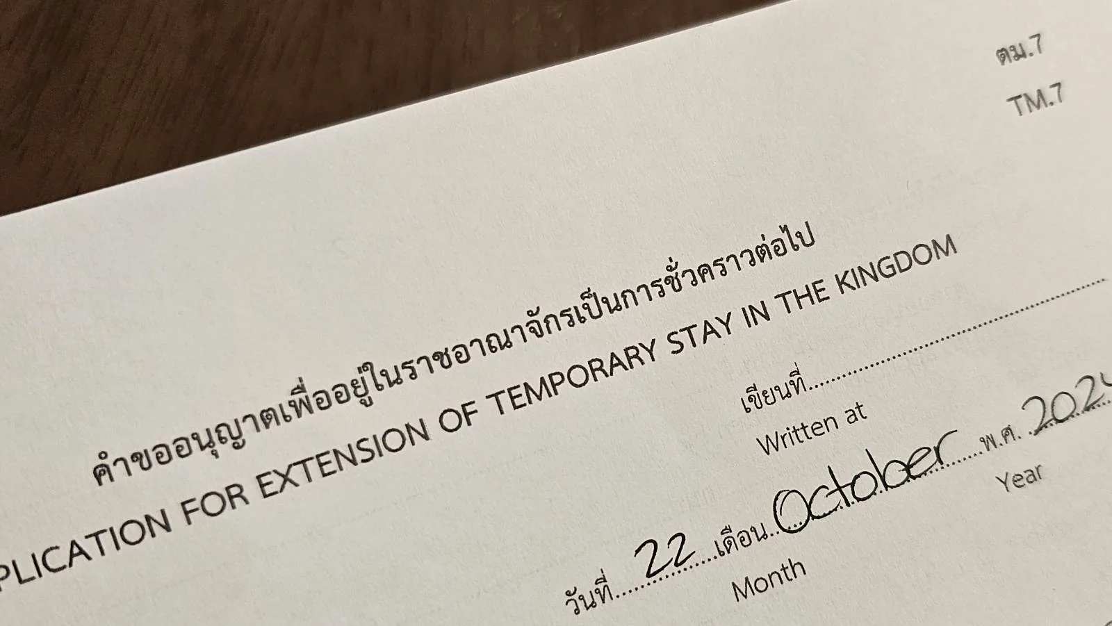 Close-up of a document titled "Application for Extension of Temporary Stay in the Kingdom." It shows a handwritten date of October 22, 2023. The text is in both Thai and English.