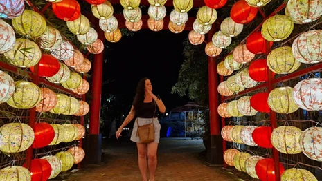 A woman walking through a lantern-lit walkway at Hoi An Memories Theme Park in Vietnam.