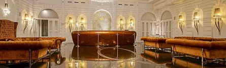 A luxurious lounge area with plush orange seating and elegant arched walls at the Prestige Hotel Budapest in Hungary.