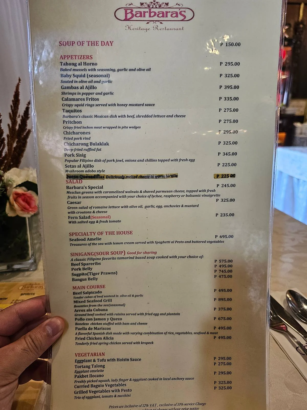 A person holds a menu from Barbara's restaurant, displaying a variety of food and drink options with prices. The menu is held in a protective cover.