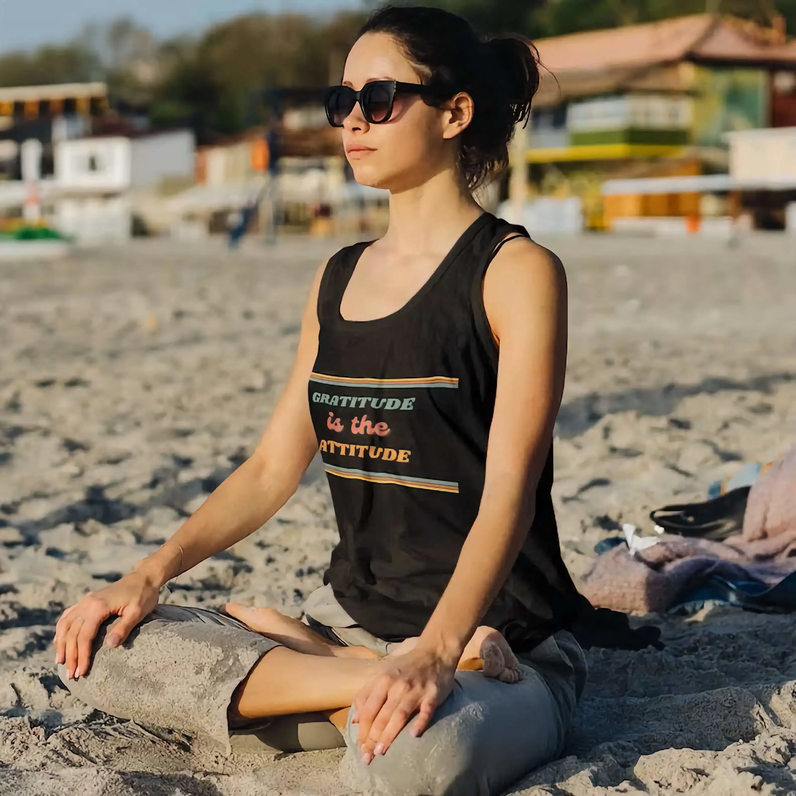 Woman meditating with sunglasses on the beach, wearing Gratitude is the Attitude Retro Tank Top | Positive Vibes Apparel.