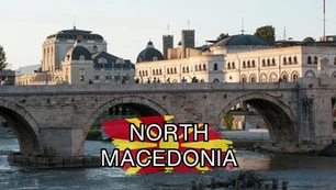 A historic stone bridge spans a river with elegant, classic buildings in the background. "North Macedonia" is prominently displayed over a red and yellow design in the center.