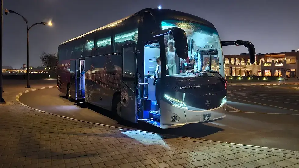 Modern air-conditioned coach bus used for the Discover Doha transit tour parked at an evening stop during a Qatar layover.