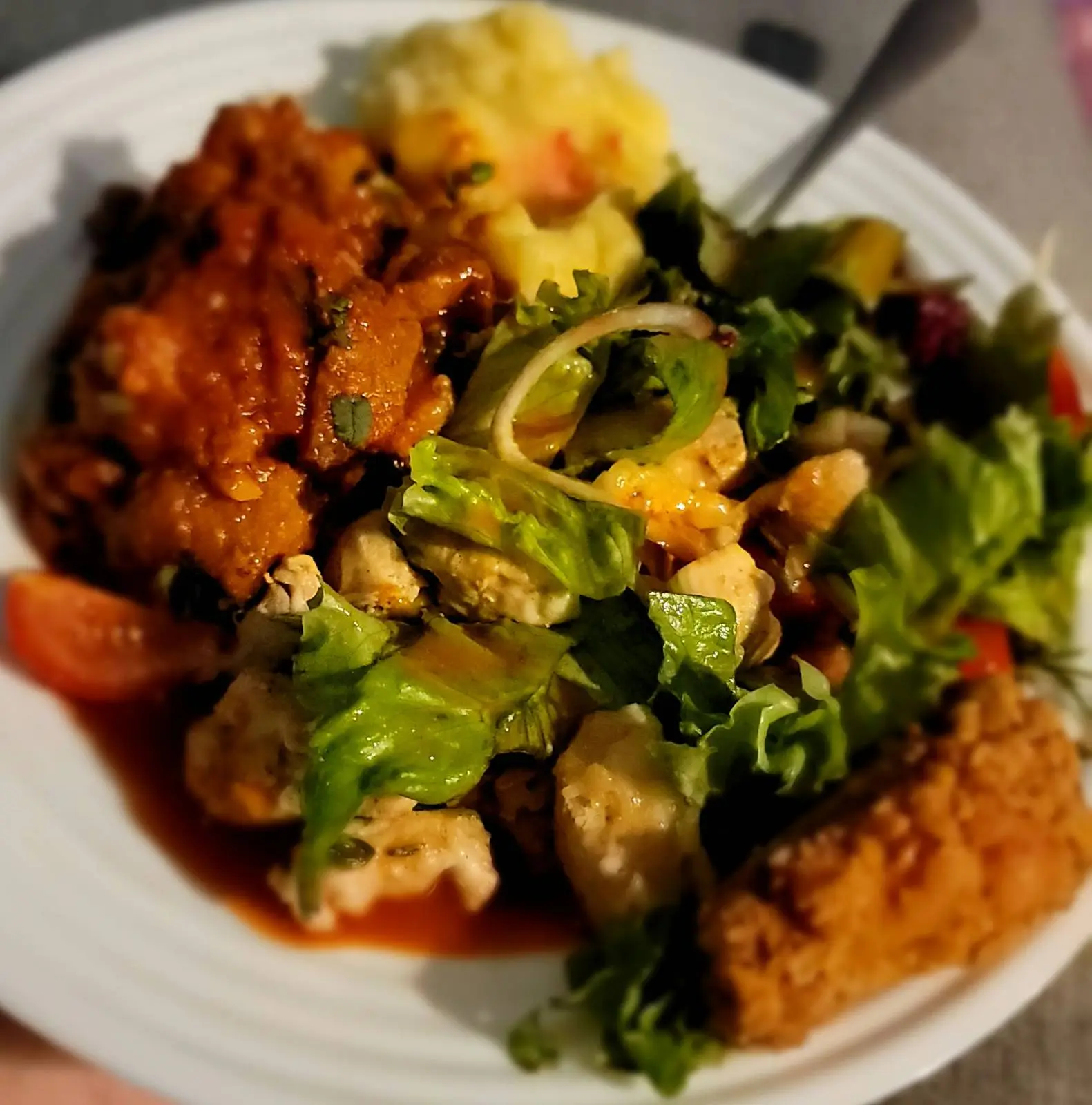 White plate of chicken wings, mashed potato, salad and orange rice.