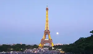 The iconic Eiffel Tower in Paris lit up at dusk under a soft twilight sky.