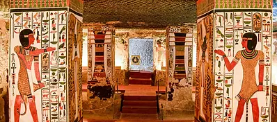Decorated columns and painted reliefs inside an ancient Egyptian tomb chamber in Cairo.