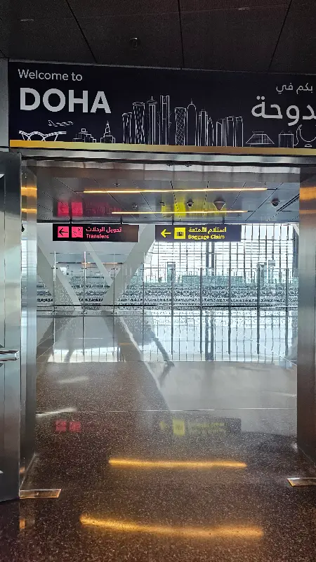 Signage welcoming international travelers to Doha at Hamad International Airport during a Qatar Airways layover.