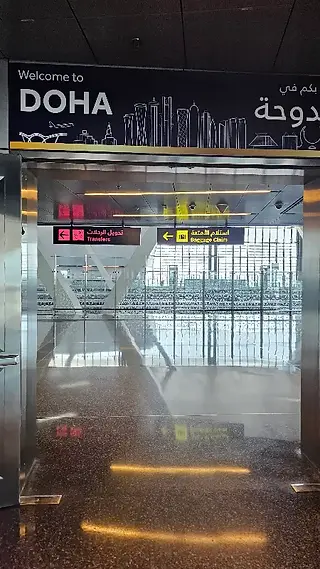 Signage welcoming international travelers to Doha at Hamad International Airport during a Qatar Airways layover.