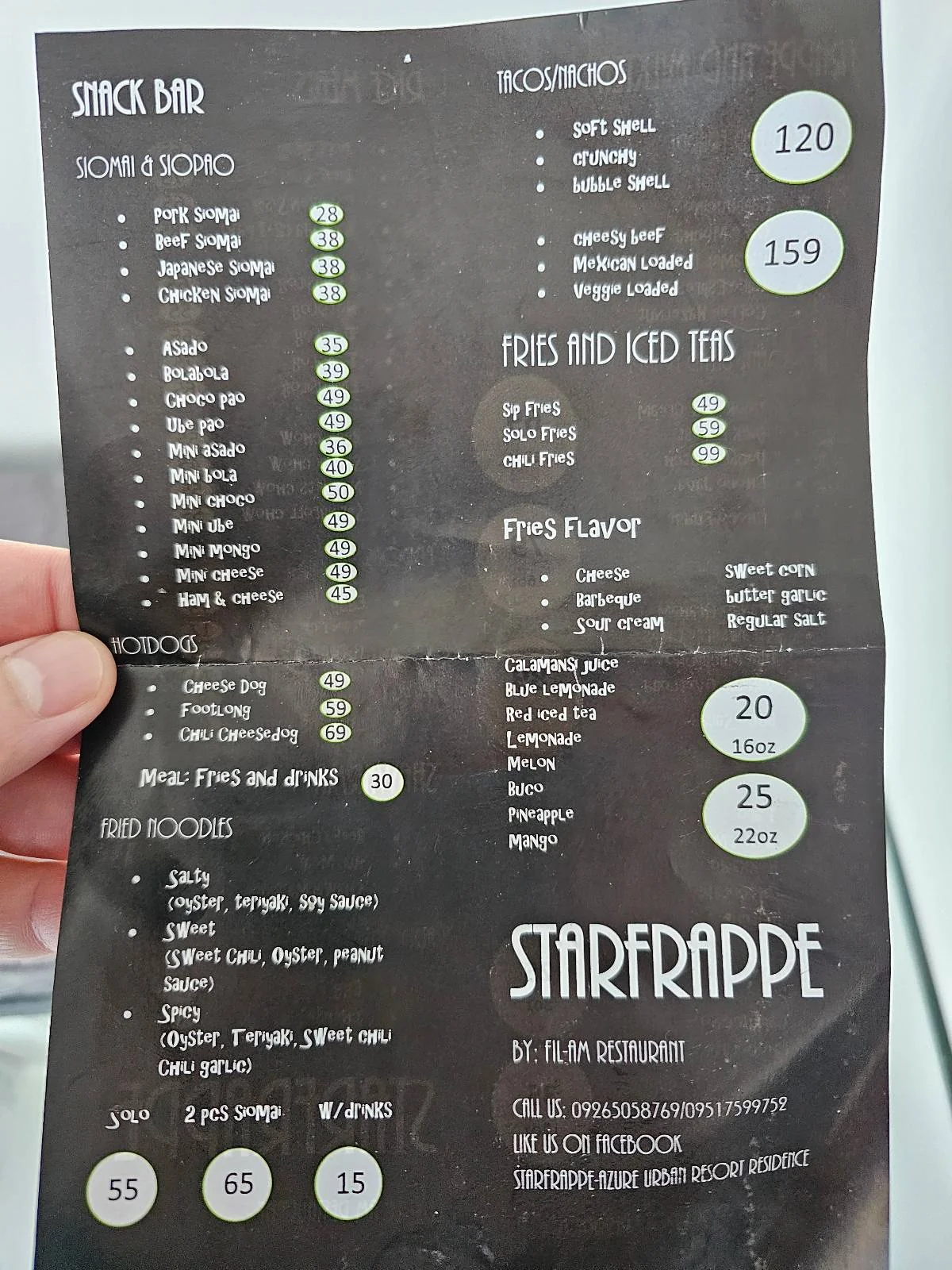 A person holds a menu titled "Starfrappe," featuring snack bar items, rice toppings, fries, and iced teas, with prices listed. The menu is organized into categories with various options and corresponding costs.