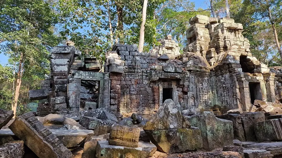 Ancient stone temple ruins with intricate carvings surrounded by lush green trees and blue sky, evoking a sense of historical decay.