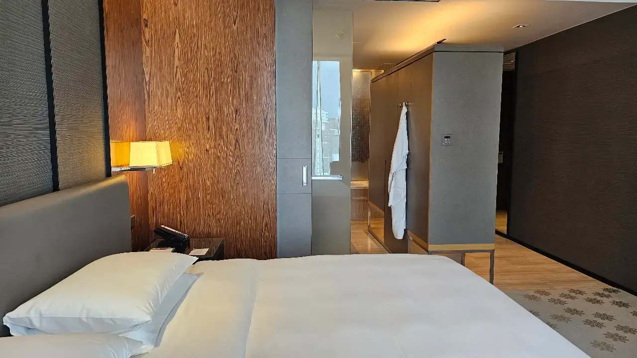 Comfortable bed with a padded headboard and bedside lighting in our upgraded Bangkok hotel room.