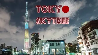 Tokyo Skytree illuminated in rainbow colors against a cloudy sky. Urban buildings in the foreground. Text: "TOKYO SKYTREE."
