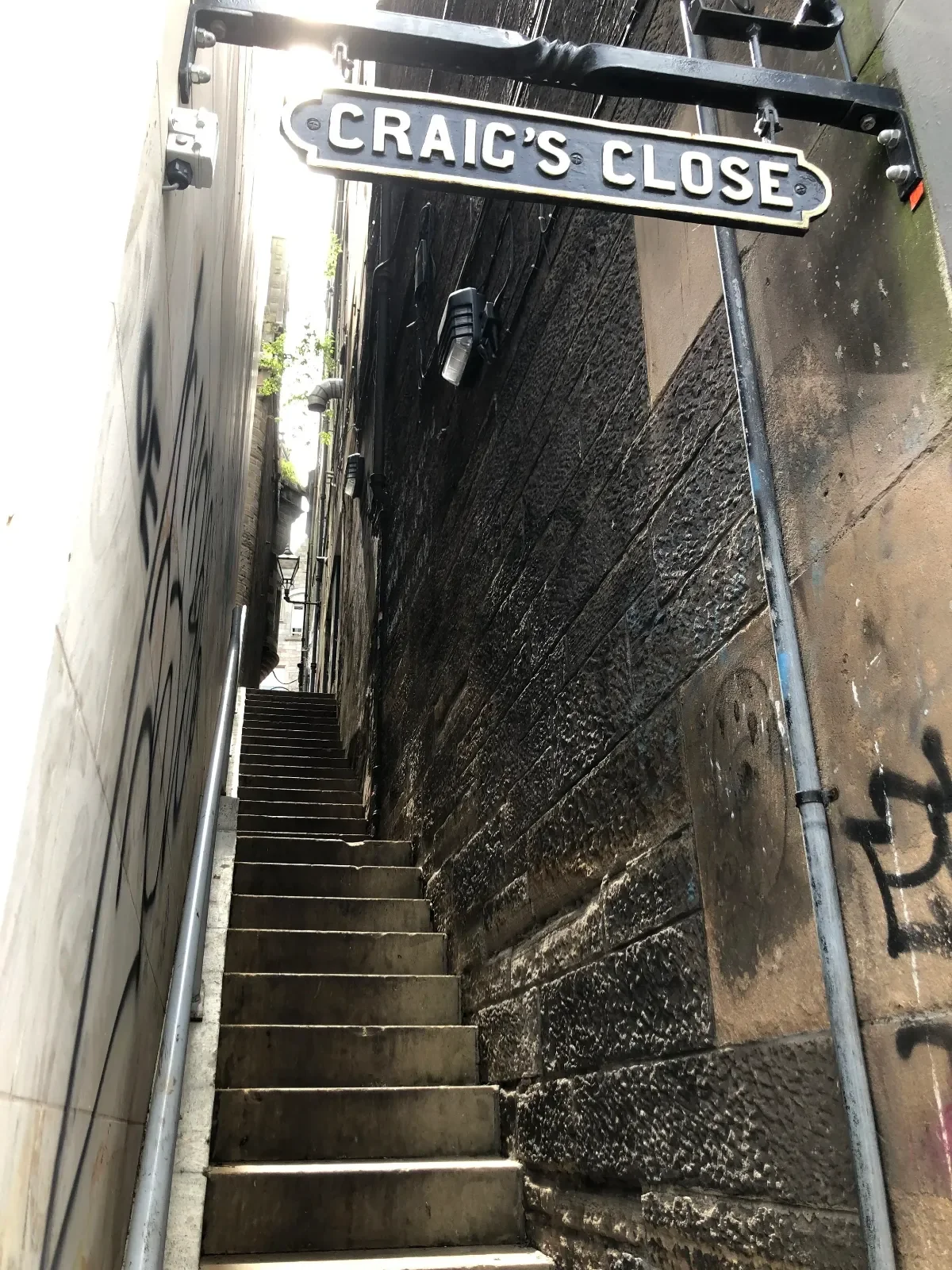 Steep stone staircase at Craig’s Close in Edinburgh, with a street sign above and narrow walls on either side.
