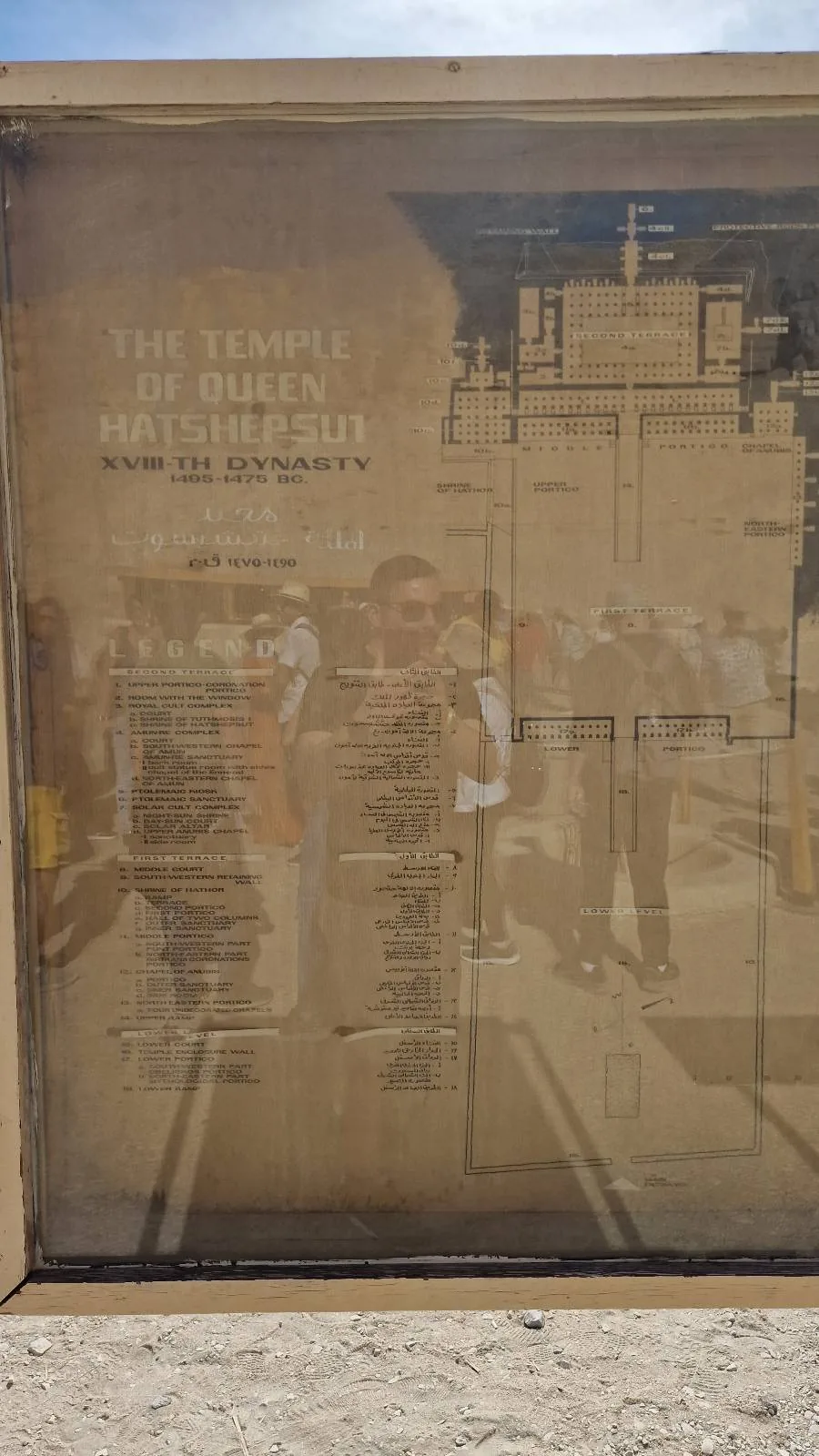 Reflection of a woman in a glass door overlaid with a faded menu and text about an event, creating a ghostly, layered street scene.