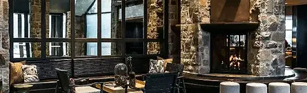 A cozy indoor lounge area with large windows and a fireplace at Fairmont Mont Tremblant in Quebec, Canada.
