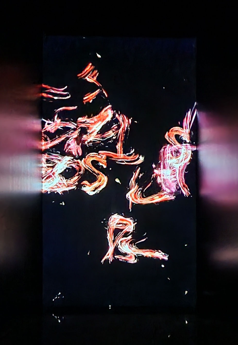 Abstract light trails in red and pink on a black background, creating dynamic shapes. The scene feels energetic and vibrant.