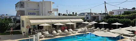 A sunny outdoor swimming pool surrounded by lounge chairs and white umbrellas at Michalis Studios & Apartments in Kos, Greece.