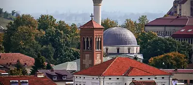 Rooftops and domes of historic buildings in Bitola, with a mosque minaret rising above the city.