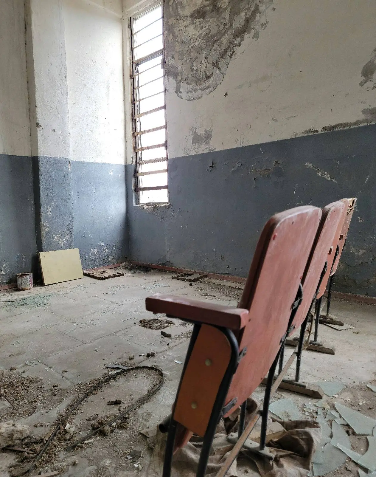 Dilapidated classroom with old chairs and peeling walls.