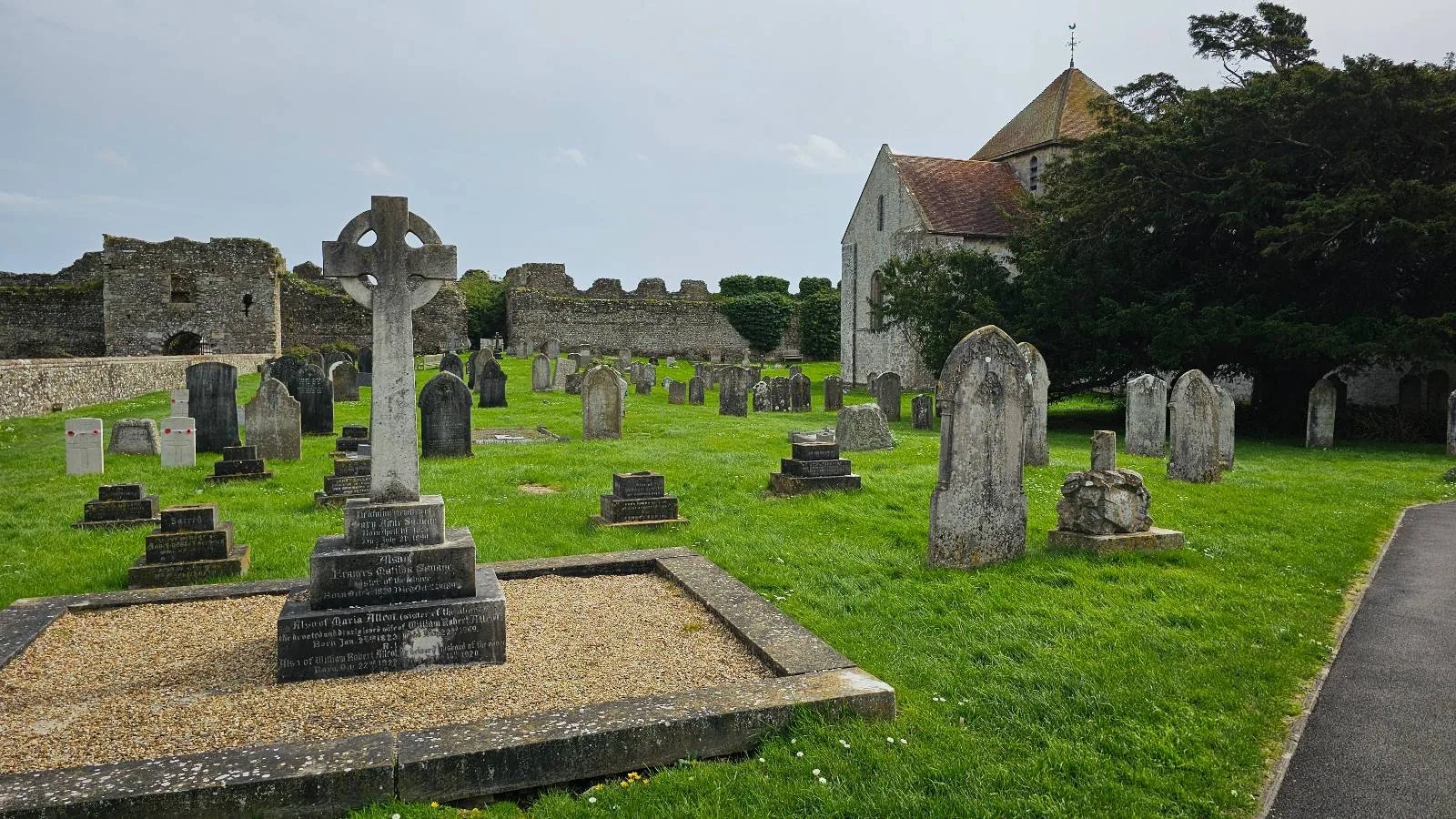 Ancient graveyard with weathered tombstones and a church in the background, surrounded by lush green grass.