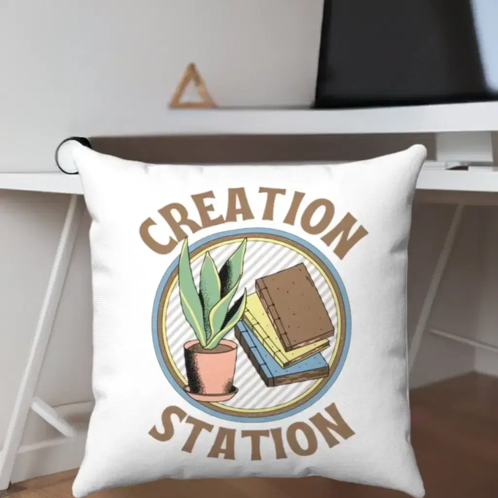 A decorative pillow with the words "Creation Station" features an illustration of a potted plant and two books.
