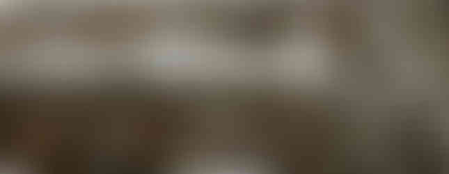 Rows of life-sized terracotta horses and soldiers stand in an ancient excavation site, partially surrounded by earth and clay walls, representing China’s famous Terracotta Army.